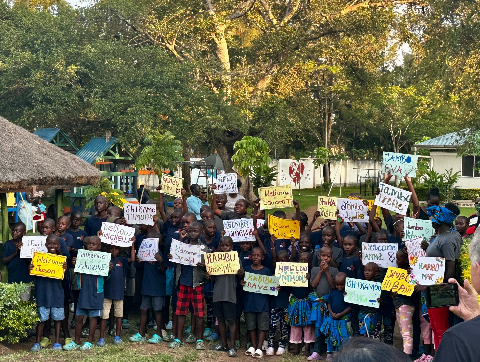 Children at CURE Kenya welcome TRIMEDX Foundation volunteers with handmade signs and smiles.
